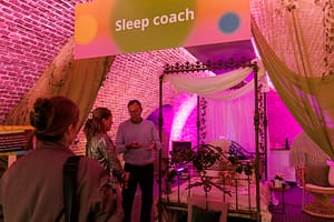 Sleep coach guiding a relaxing group session at an event with calming lights and mindfulness atmosphere