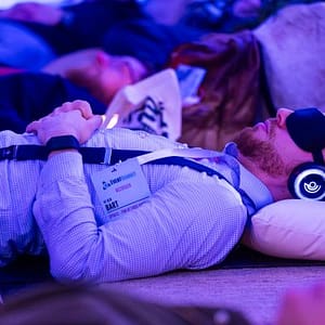 Participants wearing glowing headphones during a 9D Breathwork event, experiencing a multi-dimensional sound healing and guided meditation session in a darkened, atmospheric room