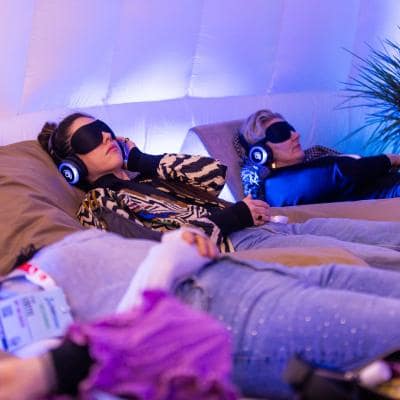 Participants wearing glowing headphones during a 9D Breathwork event, experiencing a multi-dimensional sound healing and guided meditation session in a darkened, atmospheric room