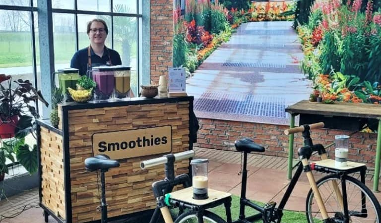 A guest pedaling the Smoothie Bike to create a fresh smoothie during an interactive event wellness experience.