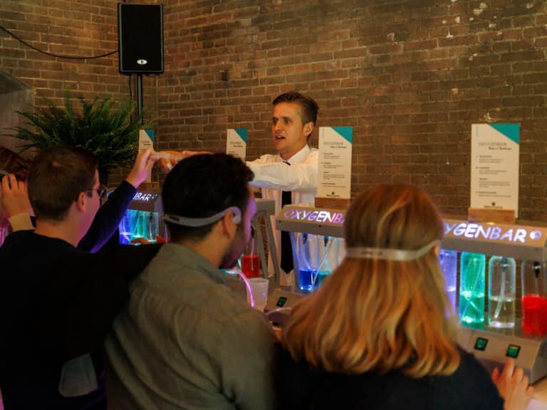 Event attendees enjoying a rejuvenating session at the Oxygen Bar, inhaling purified oxygen with aromatic scents.